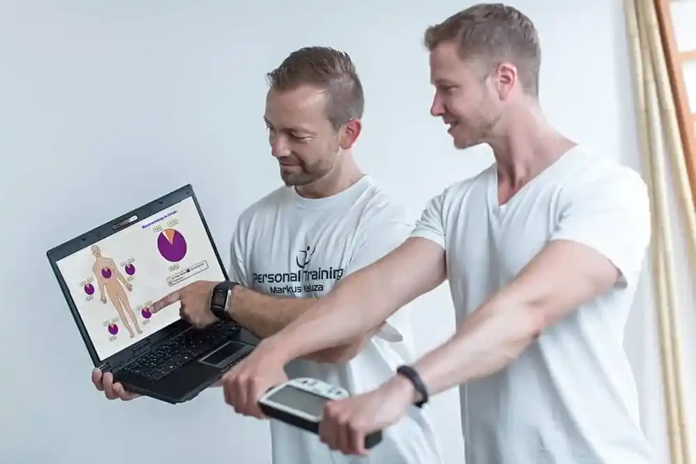 Trainer bei Durchführung einer Körperanalyse mit Klienten